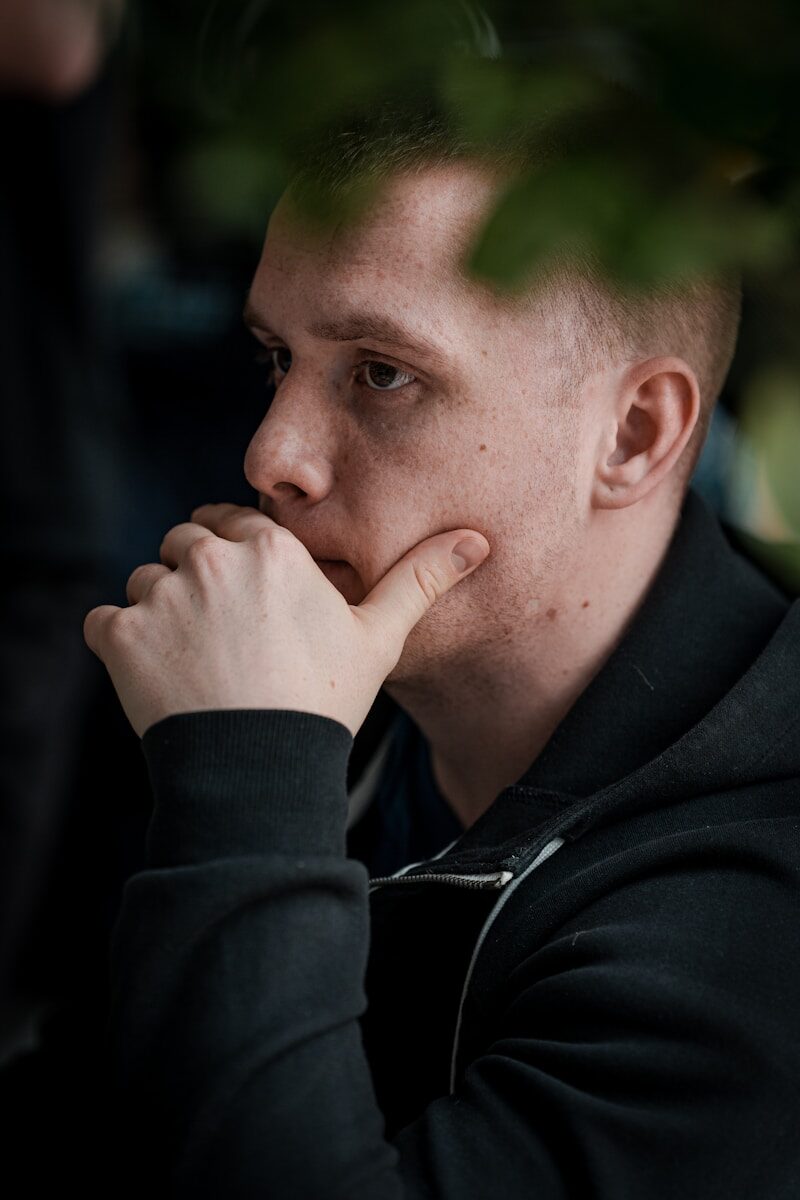 man in black jacket covering his mouth
